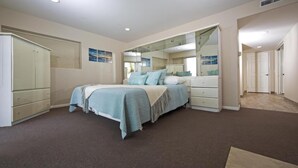 Une chambre à coucher avec un lit, une armoire, un miroir et une porte.