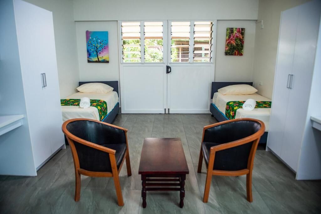 A room with two beds, a small table, and two chairs.