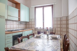 Een koelkast, een oven, een kookplaat, kookgerei, borden en bestek