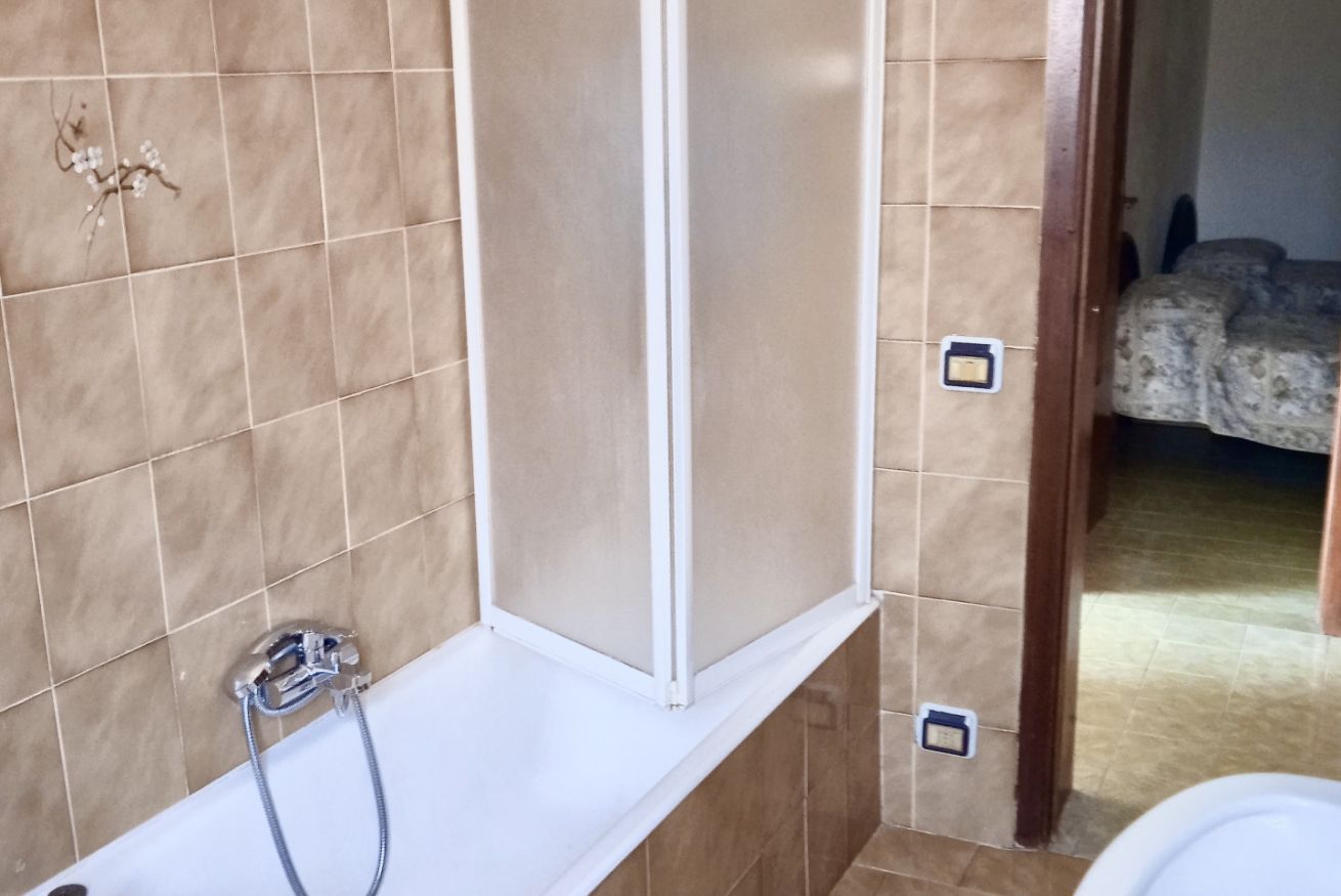 Et badeværelse med badekar, bruser og toilet.