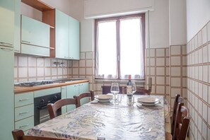 Een praktische keuken met een eetgedeelte, met een kookplaat, oven en een tafel gedekt voor twee personen.