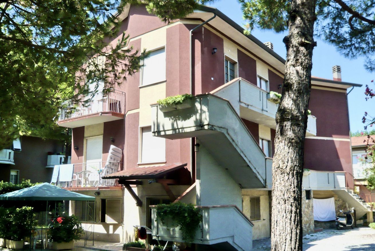 A multi-story building with balconies, a staircase, and outdoor seating.