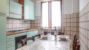 Cozinha compacta com armários verde-água, um fogão e uma mesa de jantar posta para dois.
