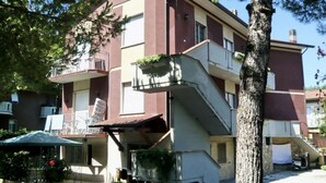 Um edifício com várias andares, varandas, área de estar externa e escadas.