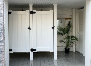 Double doors lead to a hallway with a potted plant and a brick accent wall.
