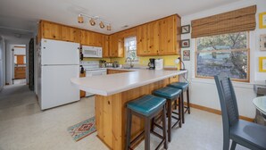 Eine Küche mit Holzausstattung, einem weißen Kühlschrank, einer Mikrowelle und einer Bar mit Barhocker.
