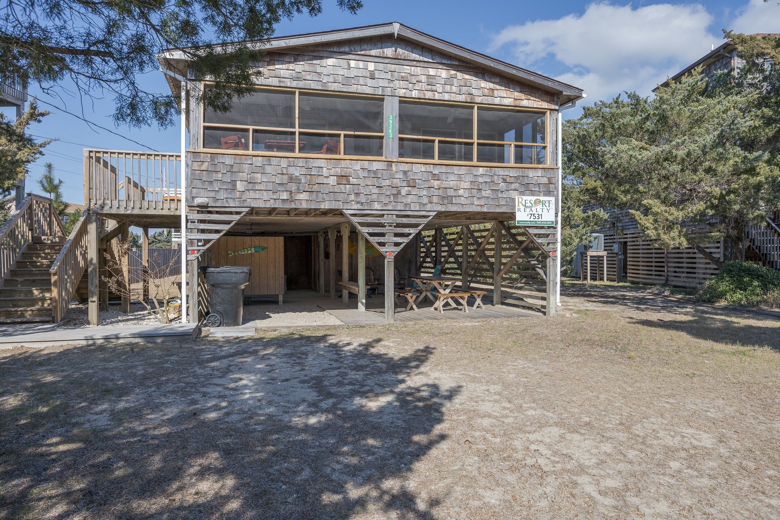 A two-story building with a stone facade, a covered outdoor area with picnic tables, and a visible address sign.