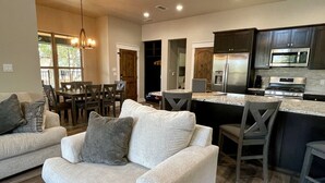 A modern kitchen with dark cabinets, stainless steel appliances, and a marble countertop. - Ranch Sunsets - Luxury Lakeview Ranch Villa at Twin Canyons Longhorn Ranch (Granbury)