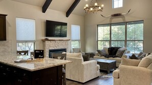 A spacious living room with a fireplace, comfortable seating, and large windows. - Ranch Sunsets - Luxury Lakeview Ranch Villa at Twin Canyons Longhorn Ranch (Granbury)