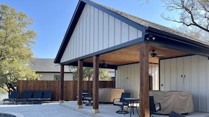 A covered patio with lounge chairs, a pool, and a wooden fence. - Ranch Sunsets - Luxury Lakeview Ranch Villa at Twin Canyons Longhorn Ranch (Granbury)