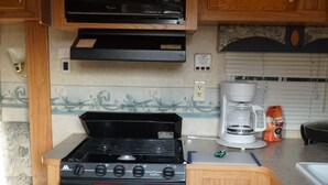 A compact kitchen with a stove, microwave, and coffee maker. - Camper in Dandridge. Close to the Smoky Mountains and Dollywood  (Dandridge)