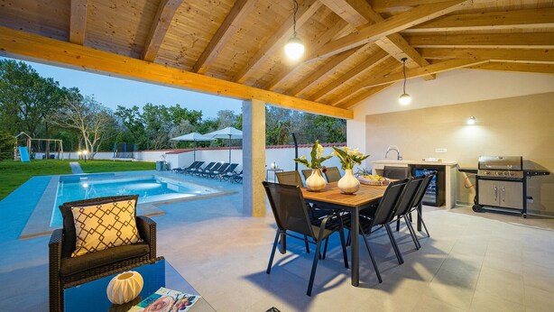 An outdoor patio with a pool, dining area, and kitchen.