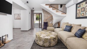A modern living room with a sofa, ottoman, and a staircase leading to an outdoor area.