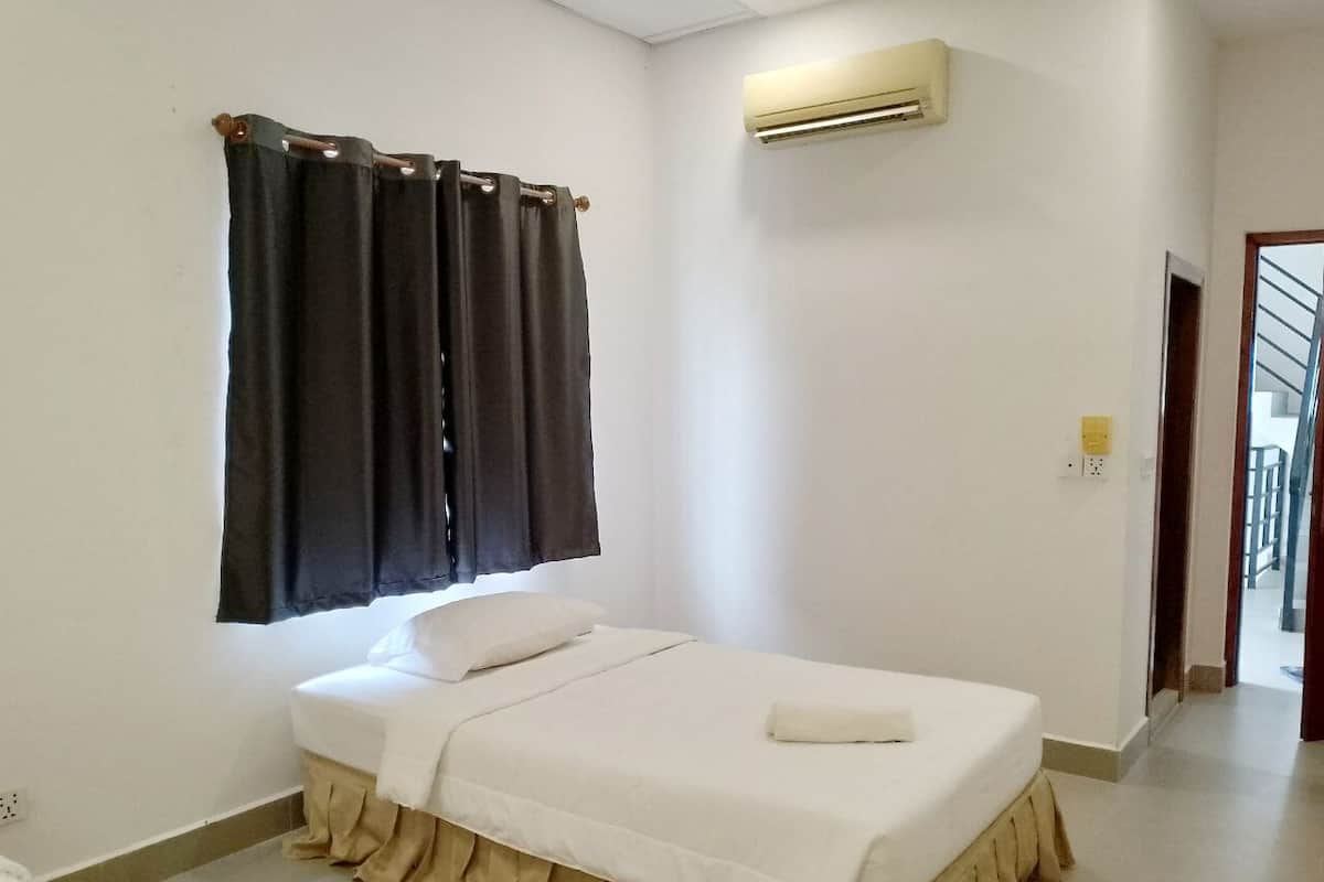A bedroom with a bed, a window with curtains, an air conditioning unit, and a door leading to another room.