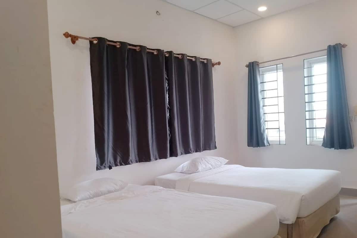 A hotel room with two single beds, a large window with curtains, and a ceiling light.