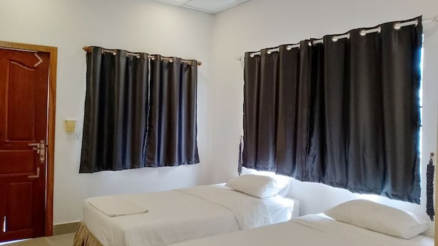 A room with two single beds, a ceiling fan, and a door. - PL Villa (Siem Reap)