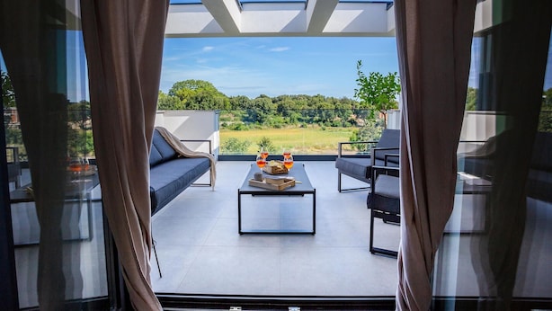 Un balcone con divano, sedie e un tavolo con bevande e snack.