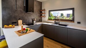 Una cucina moderna con un'isola grande, mobili scuri e una finestra che offre vista all'esterno.