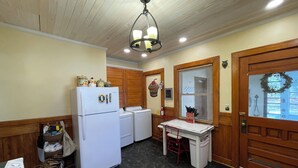 A compact kitchen with a refrigerator, washing machine, and a small table with a basket. - McKeever Lodge (Forestport)