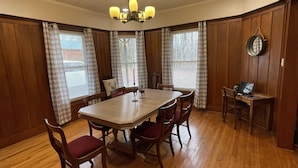 A dining area with a wooden table and chairs, a chandelier, and a laptop on a desk. - McKeever Lodge (Forestport)