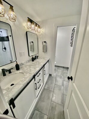 Een moderne badkamer met twee wastafels, een grote spiegel en een inloopdouche.