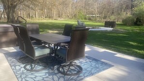 An outdoor patio with a table and chairs, surrounded by a grassy area and trees.