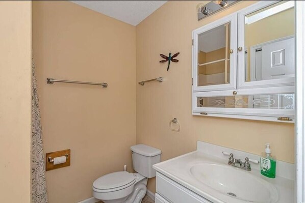 A bathroom with a toilet, sink, and mirror.