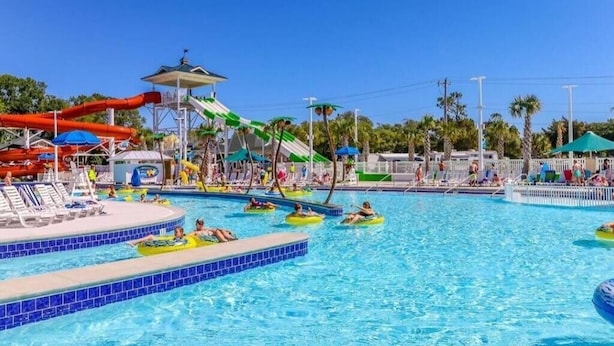 A water park with multiple pools, slides, and umbrellas.