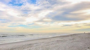 A beach with a wide sandy shore and a clear view of the ocean.
