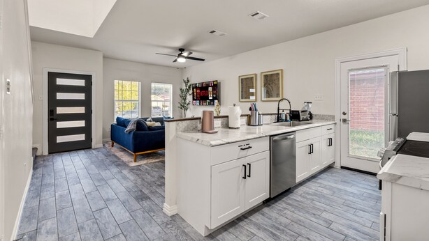 A modern kitchen with white cabinetry, a built-in dishwasher, and a large island.