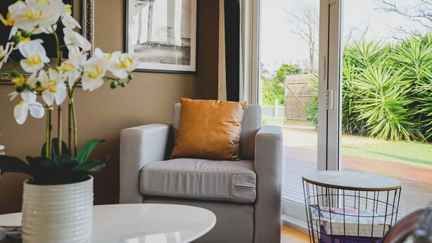 A modern living room with a grey sofa, a small round table, and a potted plant.