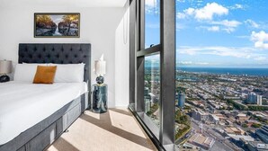Quarto com cama grande, mesa de cabeceira, abajur e quadro na parede.