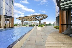A modern building with a rooftop pool, a unique circular structure, and a view of the city skyline.
