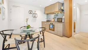 Une cuisine moderne avec des meubles en bois, une table à manger en verre et un four encastré.