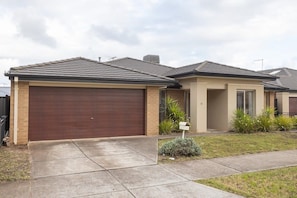 A residential house with a brown garage door, beige exterior walls, and a tiled roof.