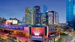 A hotel with a prominent crown logo, surrounded by high-rise buildings and a busy intersection. - Breathtaking Views 49th floor - Melbourne Square (Southbank)