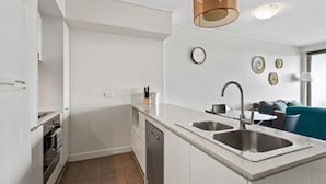 A modern kitchen with white cabinetry, a double sink, and a built-in oven.