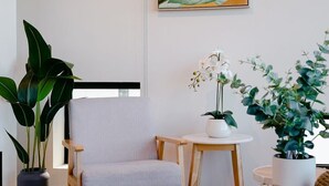 Una stanza con un divano grigio, un piccolo tavolo rotondo e piante in vaso.