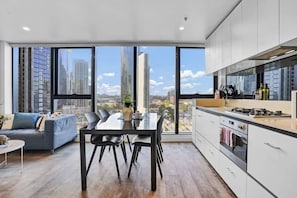 A modern kitchen with a large window, a dining area with a table and chairs, and a sofa.