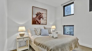 Una camera da letto con un letto, due comodini, una finestra e un quadro di un cavallo.