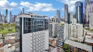 Un edificio de gran altura con fachada de vidrio moderna, rodeado de otros edificios altos en un entorno urbano.