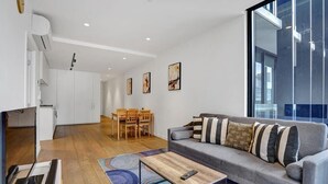 Una sala de estar moderna con un sofá gris, una mesa de centro de madera y un comedor con mesa y sillas.