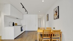 Una cocina moderna con armarios blancos, una zona de comedor con sillas de madera y una mesita.