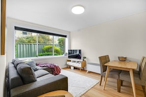 Ein modernes Wohnzimmer mit einer Couch, einem Esstisch und einem Fernseher.