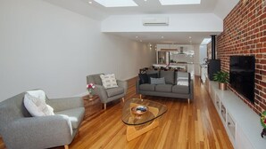 A modern living room with a sofa, a glass coffee table, and a fireplace. - SENSATIONAL Renovated Cottage in Beautiful Seddon (Seddon)