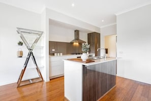 A modern kitchen with a central island, wooden flooring, and a visible stove.