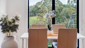 A room with a large window, a table with chairs, and a vase with flowers. - Bundoora Family Home near Uni Hill (Bundoora)