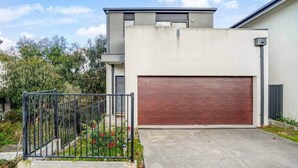 A modern two-story building with a garage door, a concrete driveway, and a metal fence. - Bundoora Family Home near Uni Hill (Bundoora)