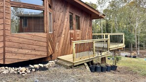 Una cabaña de madera con terraza y plantas en macetas.
