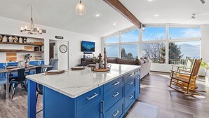 Una cucina moderna con mobili blu, una grande isola e un'area pranzo con vista.